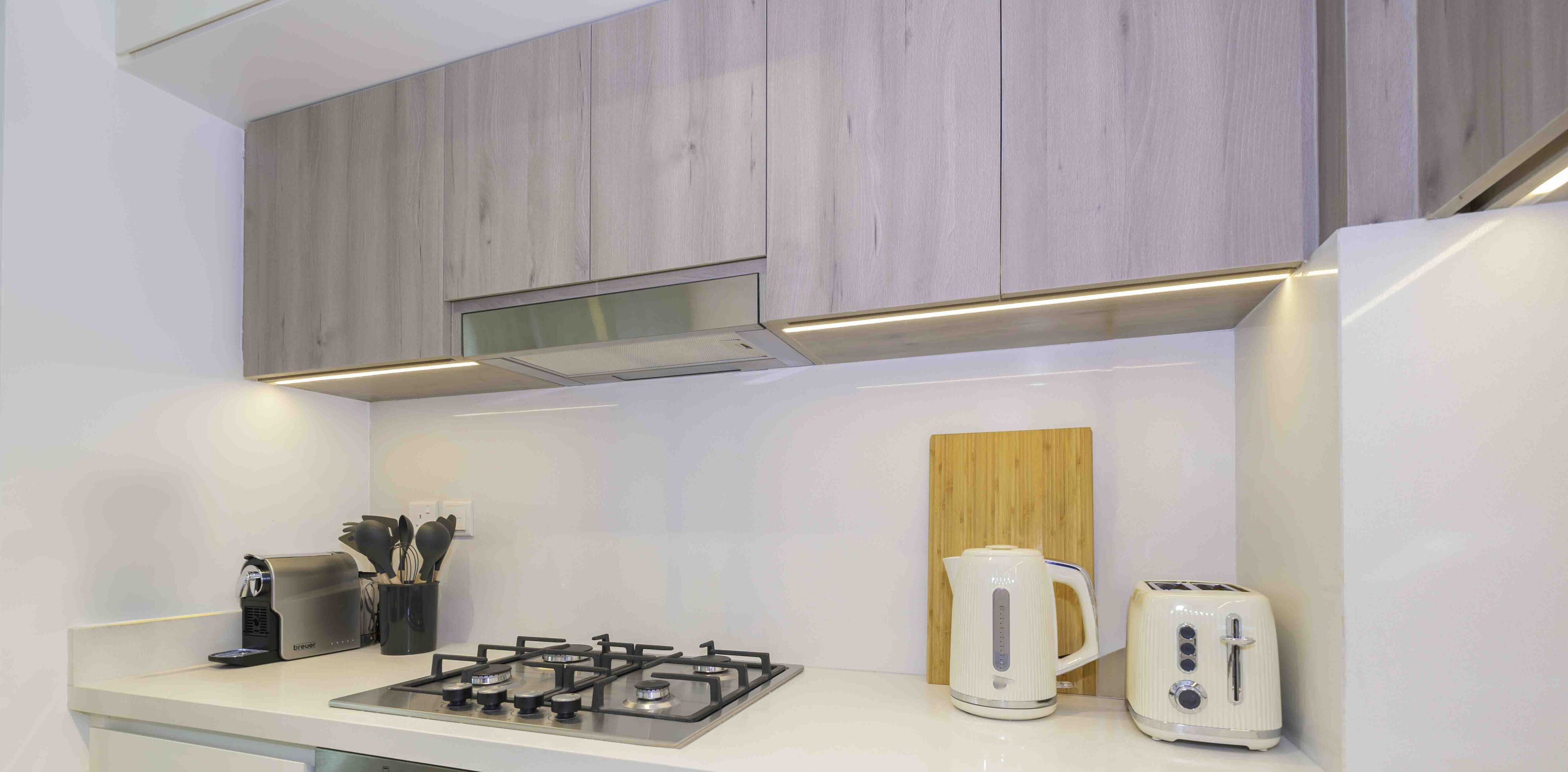 A modern kitchen with a gas stove, a kettle, and a toaster on the counter.