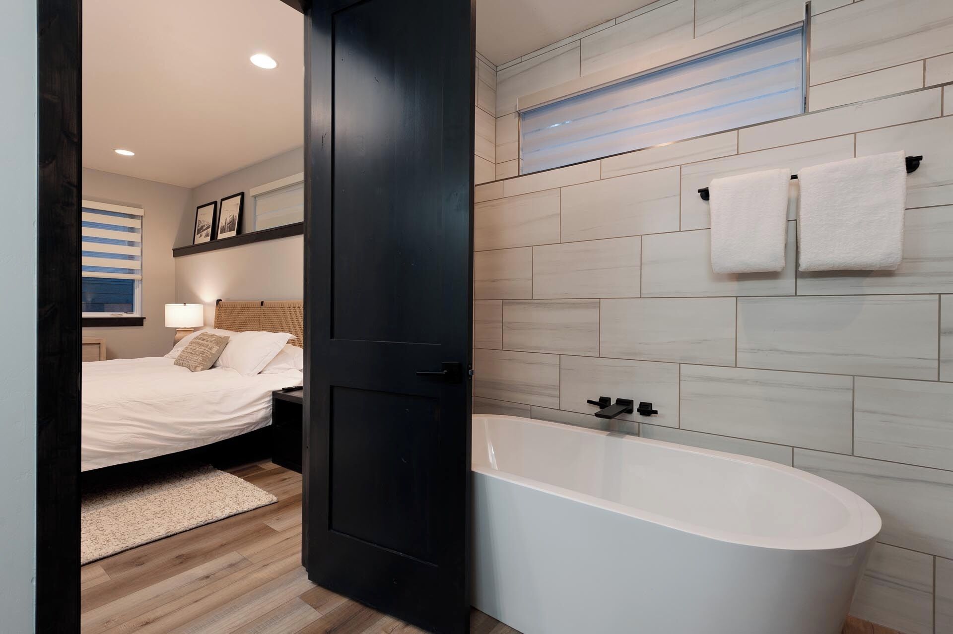 Une salle de bain moderne avec une baignoire sur pieds, un espace douche et un lit avec une tête de lit.