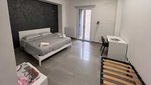 A modern bedroom with a bed, bedside tables, a desk, and a chair. - Le Camere dell'Emiro 2 (Castronuovo di Sicilia)