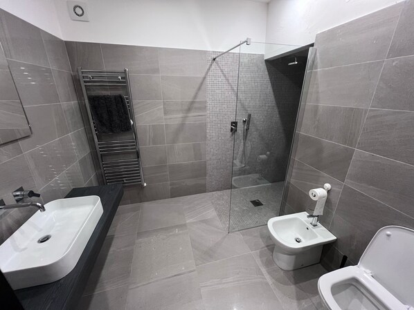 A modern bathroom with a large bathtub, a separate shower area, and a bidet.