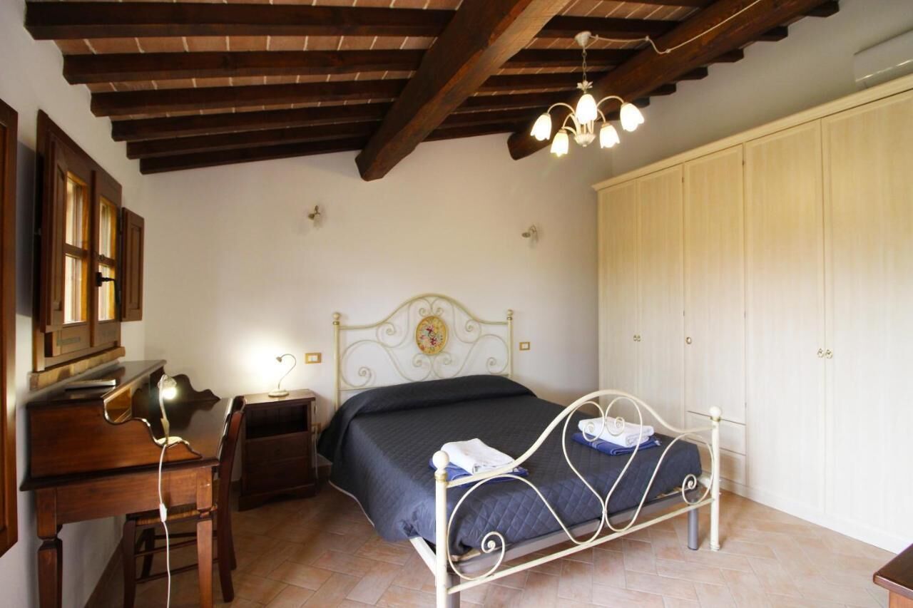 Une chambre à coucher comprenant un lit, un bureau, une chaise, une armoire et un lustre.