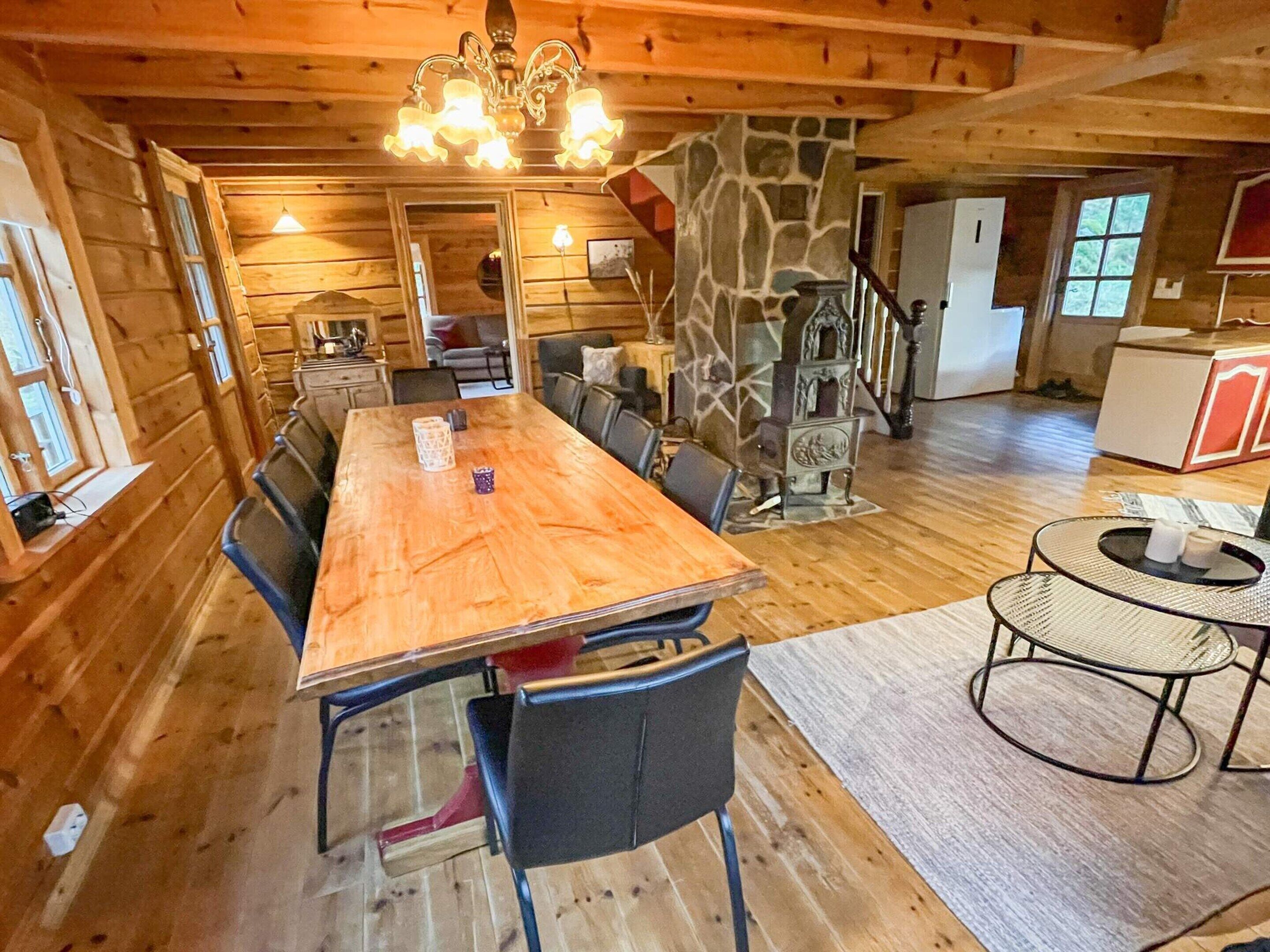 Un interior de madera con una amplia mesa de comedor, sillas, una pared de acento de piedra y una araña.