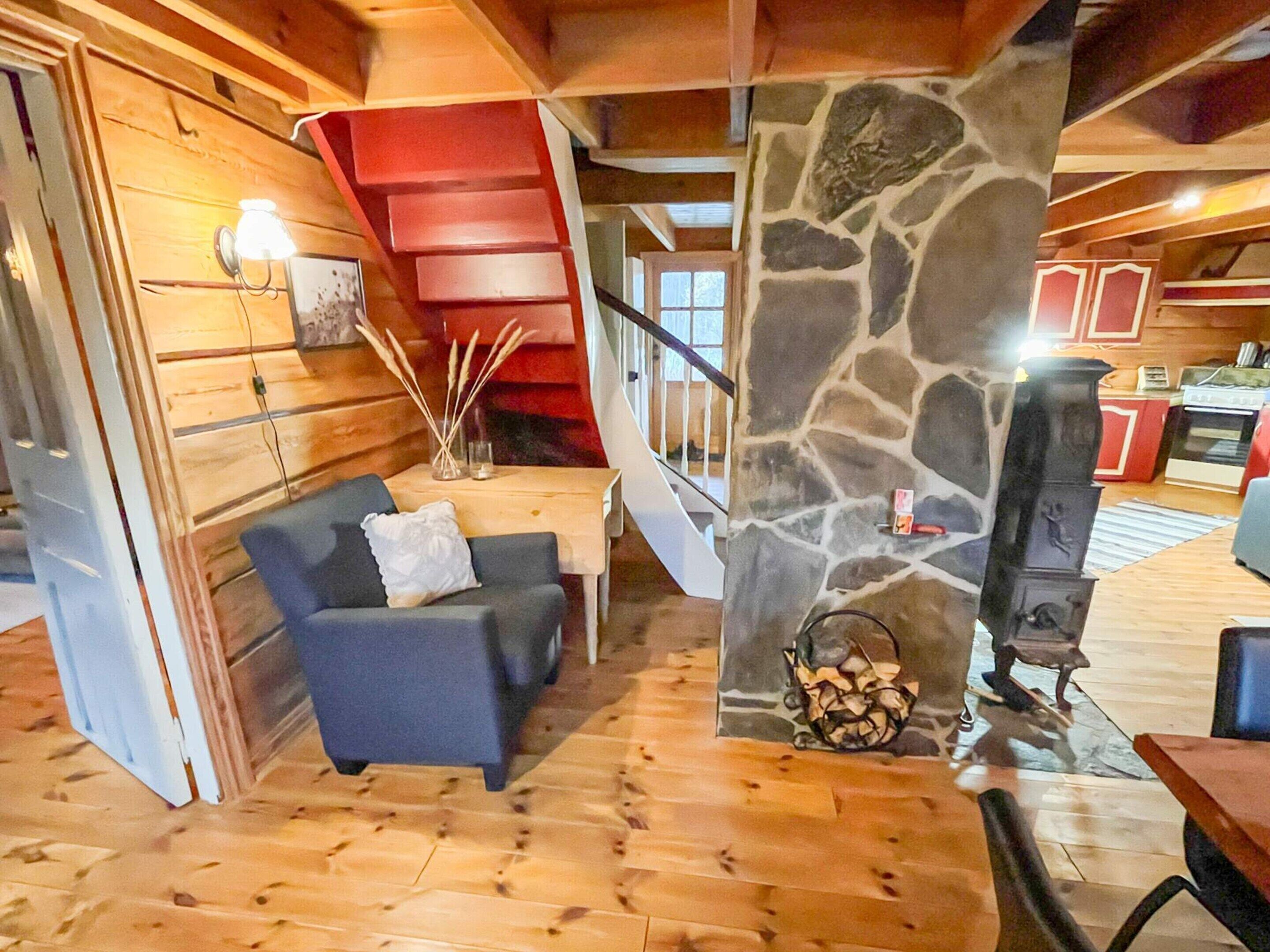 Un salon chaleureux avec un pilier en pierre, une cheminée et un escalier en bois.