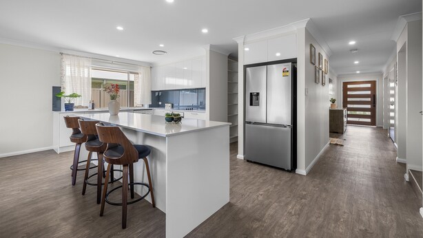 A modern kitchen with a central island, bar stools, and a refrigerator. - Air Conditioning *  Secured Parking * BBQ * No Linen (South West Rocks)