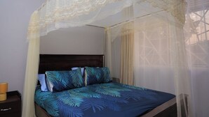 A bed with a canopy, a nightstand, and a lamp. - Najjera, Kampala 1bed With Balcony, Wifi & Parking (Kampala)