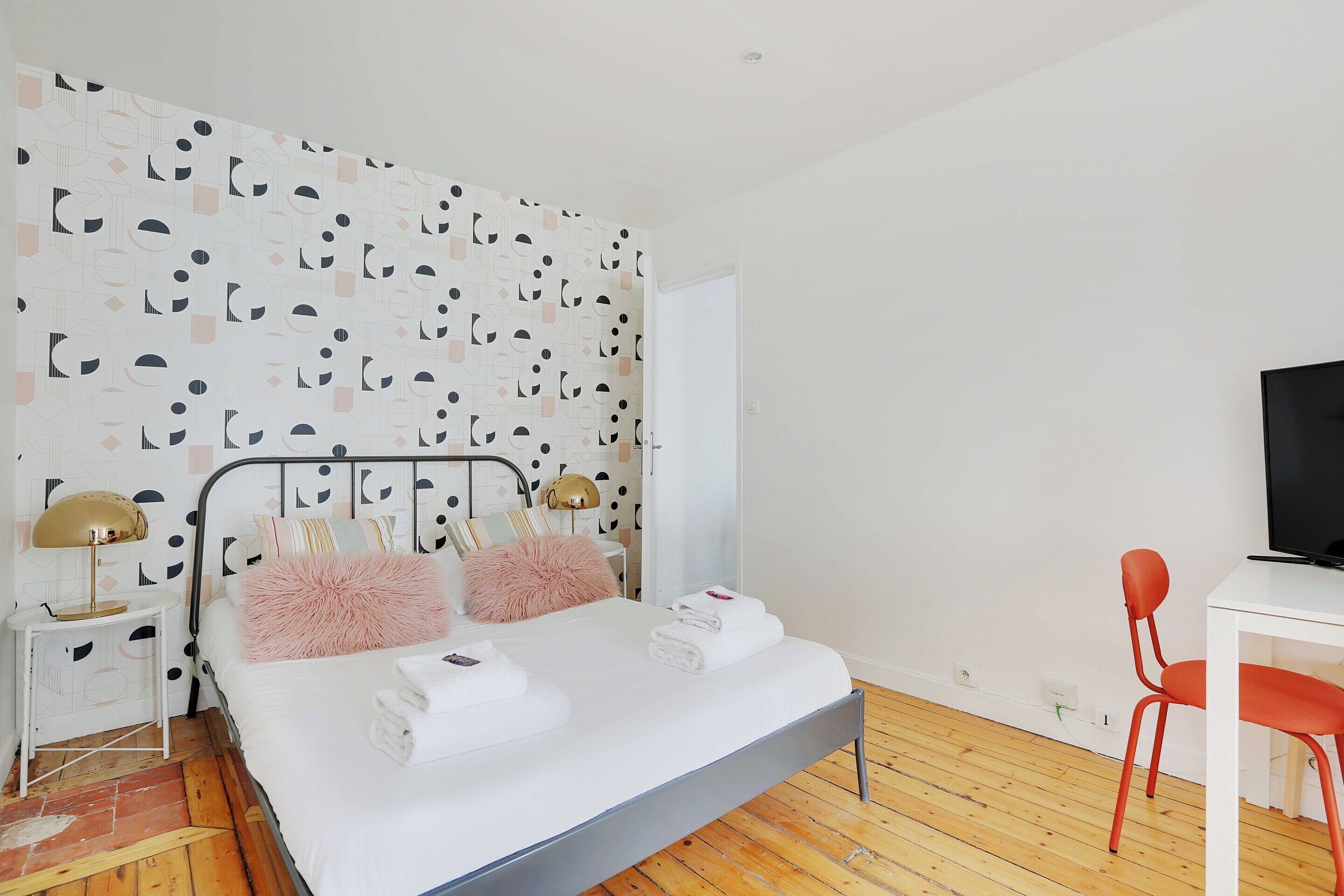 A bedroom with a bed, bedside tables, a desk, and a chair.