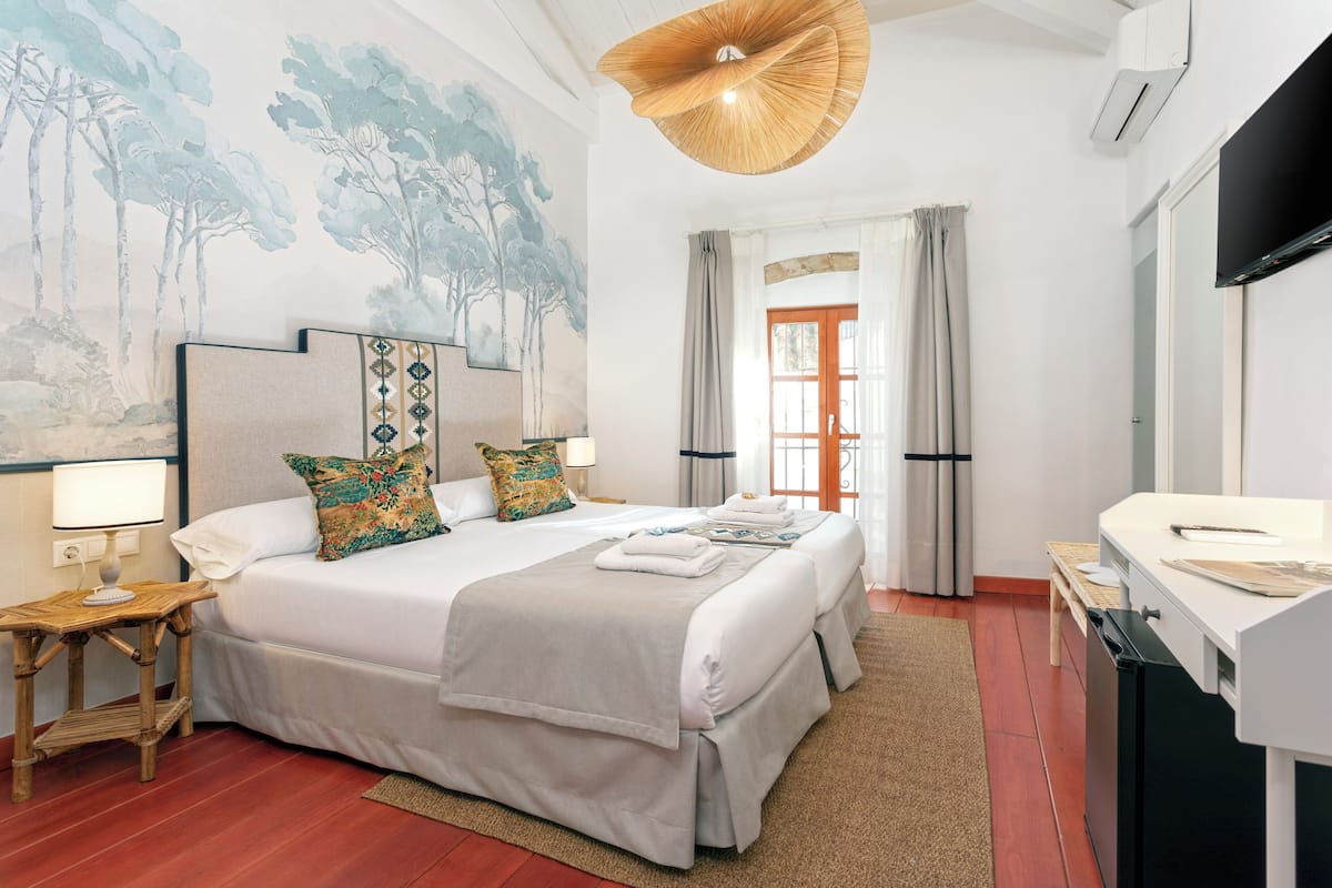 Una habitación de hotel con una cama grande, un escritorio, un televisor y una pared con un cuadro.