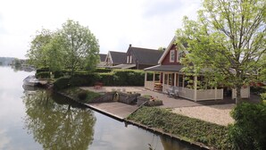 Ein Anwesen am Seeufer mit Steg, überdachter Terrasse und einem kleinen Boot.