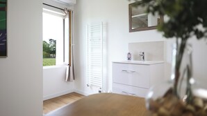 A modern bathroom with a white vanity, a towel rack, and a window with curtains. - Chambre d’hôtes de Austerlitz (Libourne)