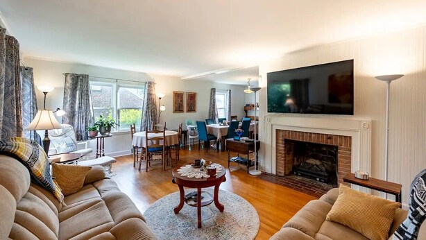 A living room with a fireplace, sofa, dining table, and TV.