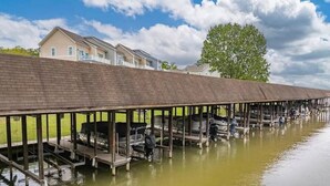 A covered boat dock with several boats and a house in the background. - Game Room! Pontoon Rental~Boat Slip~Fire Pit

 (Littleton)