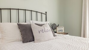 A bed with a metal headboard, pillows, a sign with the text "SUNSHINE and the LAKE is all I need", and a wall clock. - Game Room! Pontoon Rental~Boat Slip~Fire Pit

 (Littleton)