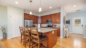A kitchen with wooden cabinets, a granite countertop, a stainless steel refrigerator, and a microwave. - Game Room! Pontoon Rental~Boat Slip~Fire Pit

 (Littleton)