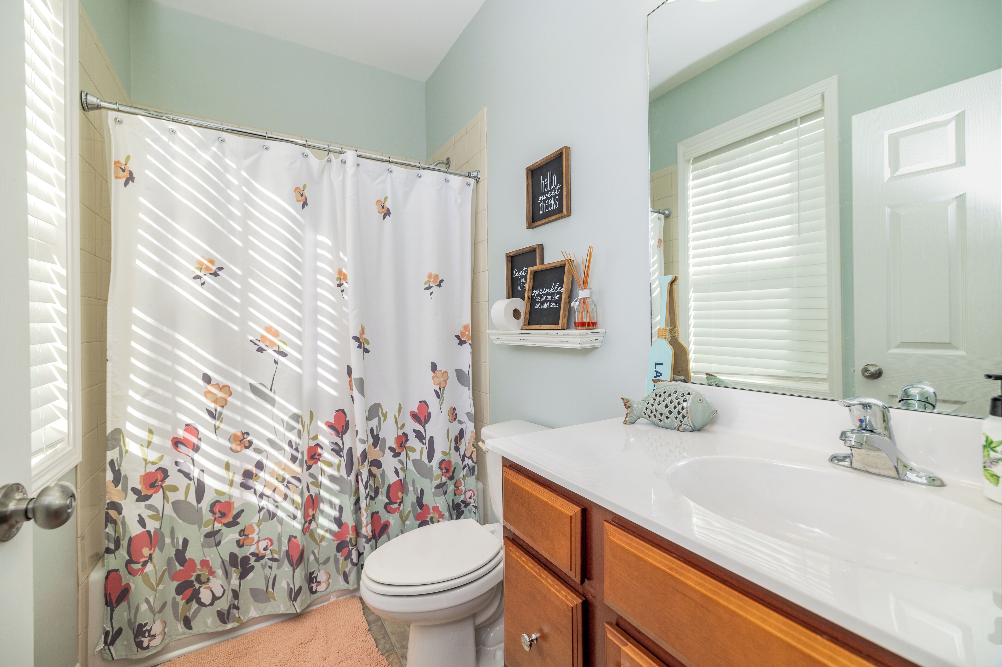 Une salle de bain équipée d’un rideau de douche, de toilettes, d’un lavabo, d’un meuble-lavabo et d’un miroir.