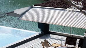 A modern outdoor pool area with a wooden deck, two lounge chairs, and a small table. - Yakamoz qianchuan Hotel (Hangzhou)