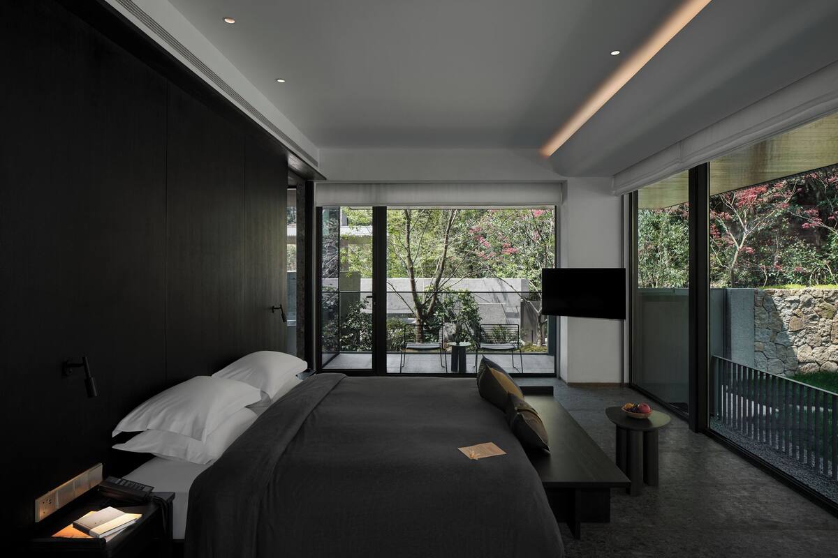 A modern bedroom with a large bed, bedside table, and a TV.