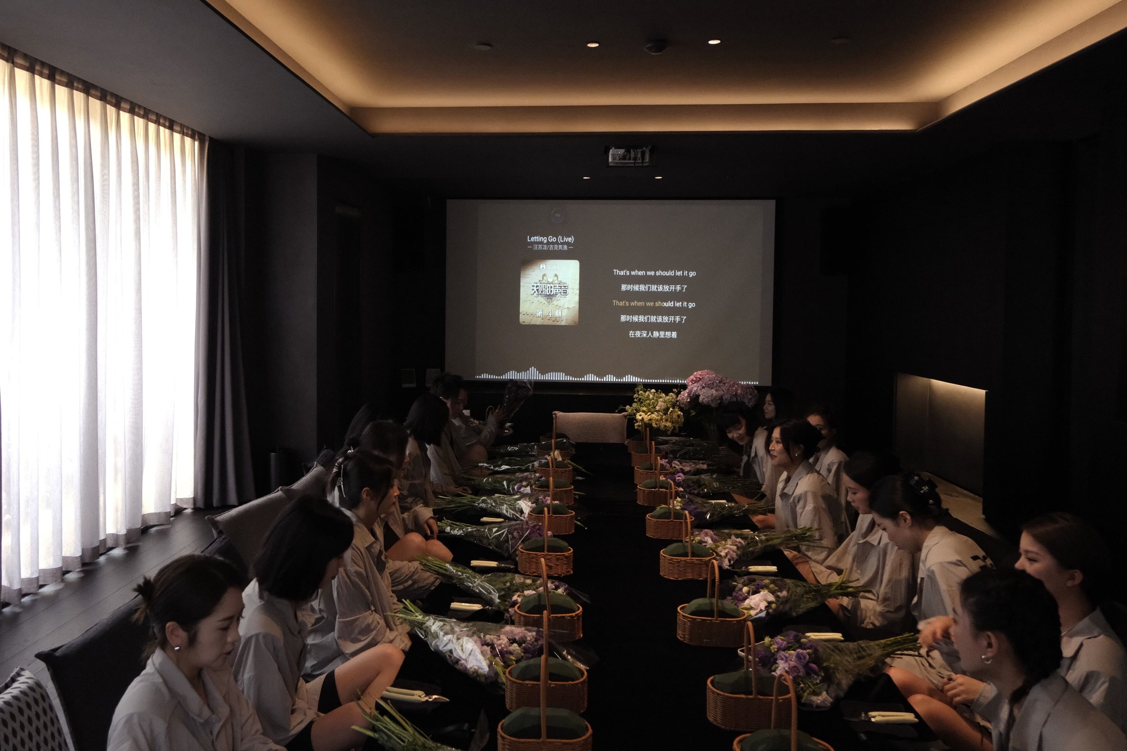 A conference room with a long table, attendees seated, and a presentation screen in the background.