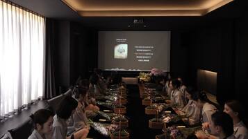 A conference room with a long table, attendees seated, and a presentation screen in the background.