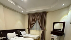 A hotel room with two single beds, a small desk, a mirror, and a refrigerator. - Taj Aldahabia Hotel - Makkah - Al Rawda فندق تاج الذهبية - مكة - الروضة (Makkah)