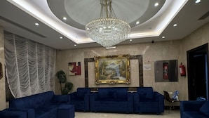 A spacious lobby with a large chandelier, blue sofas, a marble floor, and a framed painting on the wall. - Taj Aldahabia Hotel - Makkah - Al Rawda فندق تاج الذهبية - مكة - الروضة (Makkah)