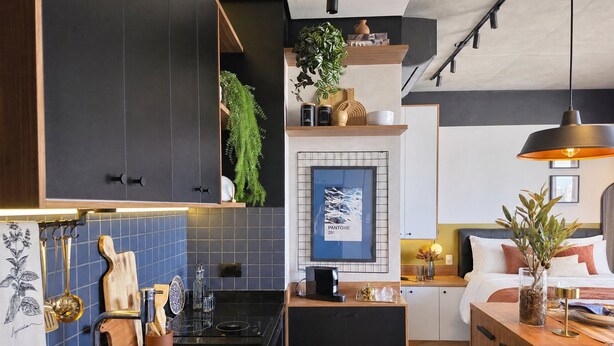 Una cucina moderna con un piano di lavoro nero, lavello in acciaio inossidabile e pensili in legno.