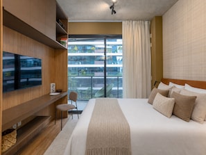 A modern hotel room with a large bed, a flat-screen TV mounted on the wall, a small seating area, and a balcony with a view of the city. - VN Millennium (São Paulo)