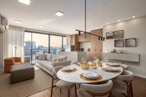 A modern living room with a dining area, large windows, and a city view. - VN Millennium (São Paulo)