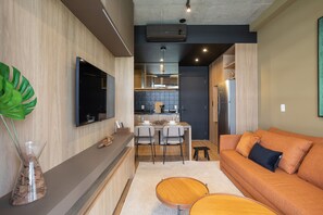 A modern kitchen with a dining area, a sofa, and a TV mounted on the wall. - VN Millennium (São Paulo)
