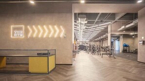 Una palestra con pavimento in legno, attrezzature per esercizi e una reception.