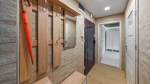A hallway with wooden paneling, a mirror, and a door leading to a room. - Apartamenty Sun & Snow 1000-lecia Państwa Polskiego (Wladyslawowo)