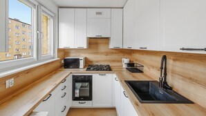 A modern kitchen with white cabinets, a built-in oven, a microwave, and a gas stove. - Apartamenty Sun & Snow 1000-lecia Państwa Polskiego (Wladyslawowo)
