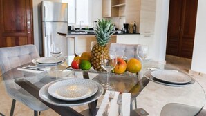 Une table à manger dressée avec des assiettes, des couverts et un centre de table composé de fruits.