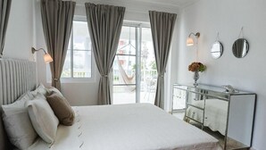 Une chambre avec un grand lit, une commode et une fenêtre avec des rideaux.