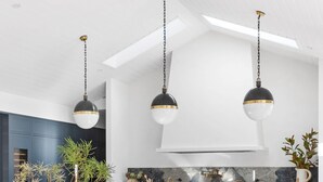 Een moderne keuken met een houten eettafel, rieten stoelen en hanglampen.
