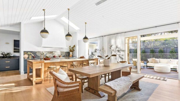 Een ruime keuken met een centraal eiland, een houten eettafel en rieten stoelen.