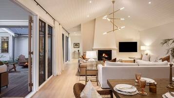 A spacious living room with a fireplace, a dining area with a table set for four, and a large sliding glass door leading to an outdoor deck.