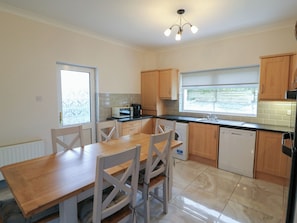 A modern kitchen with a dining table, chairs, a microwave, a coffee maker, and a dishwasher.