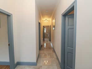 A hallway with a tiled floor, light-colored walls, and a door on the right.