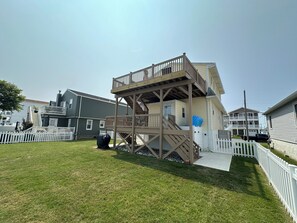 Enjoy the expansive deck with a staircase leading to the upper level, surrounded by a well-maintained lawn and a white picket fence.
