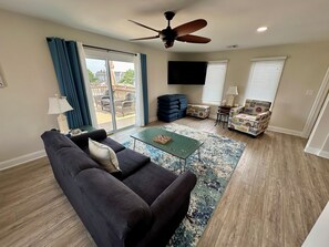 Relax in this inviting living room with a sofa, armchair, and coffee table, perfect for unwinding with a view of the outdoor patio.