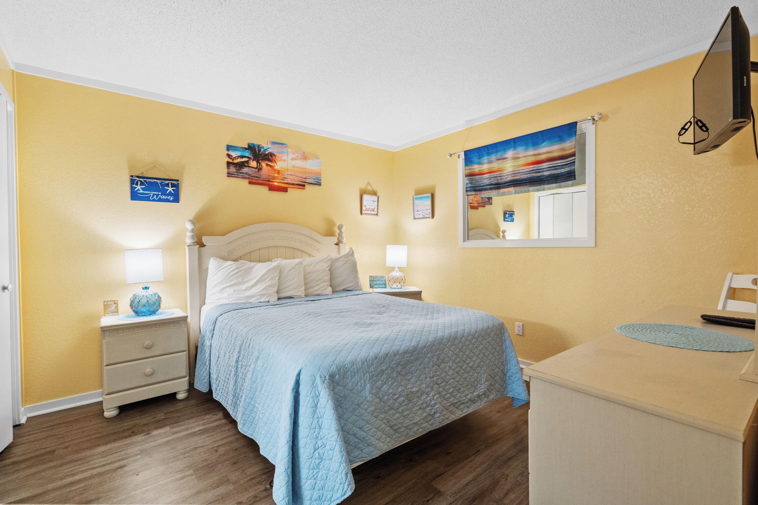 Une chambre à coucher avec un lit, des tables de chevet, une commode et une fenêtre donnant sur un beau paysage.