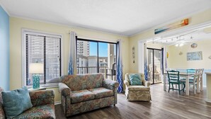 Un salón amplio con un sofá grande, un sillón más pequeño y una zona de comedor con mesa y sillas.
