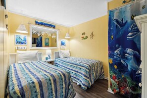 Une chambre avec deux lits, un miroir et une fresque représentant des créatures marines.