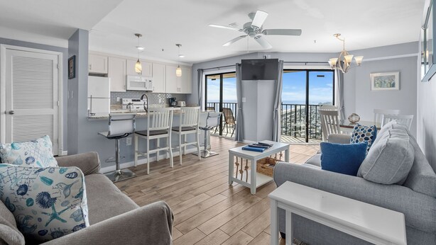 A spacious living area with a balcony, a kitchen, and a dining area. - T1216 at the Myrtle Beach Resort (Myrtle Beach)