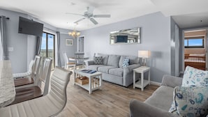 A modern living room with a grey sofa, a white coffee table, and a TV mounted on the wall. - T1216 at the Myrtle Beach Resort (Myrtle Beach)