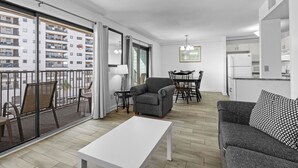 A modern apartment with a balcony, a dining area, a kitchen, and a living room.