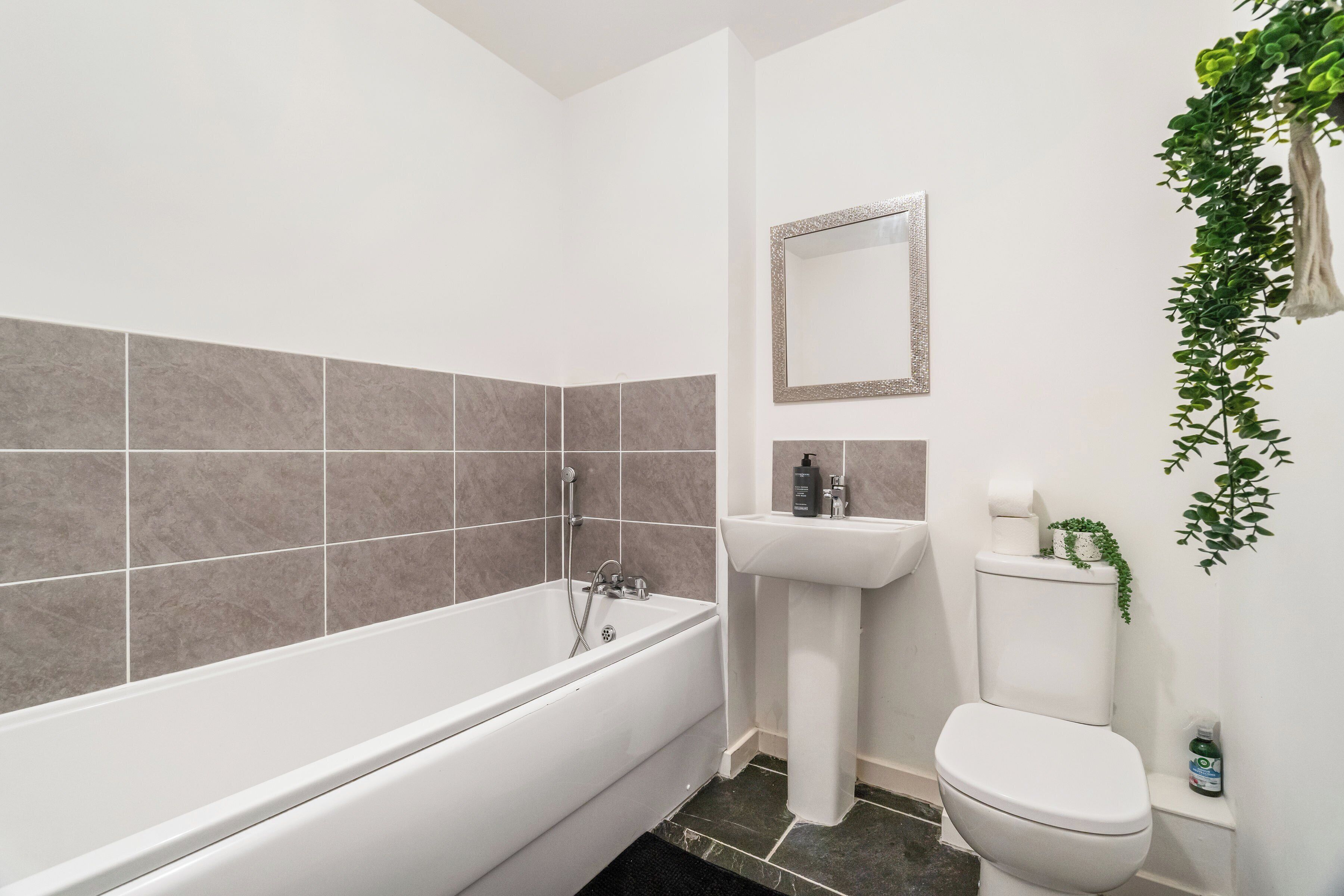 Ein Badezimmer mit Badewanne, Waschbecken, Toilette und Spiegel.