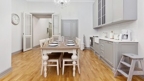 A modern kitchen with white cabinetry, a dining table set for four, and a chandelier.