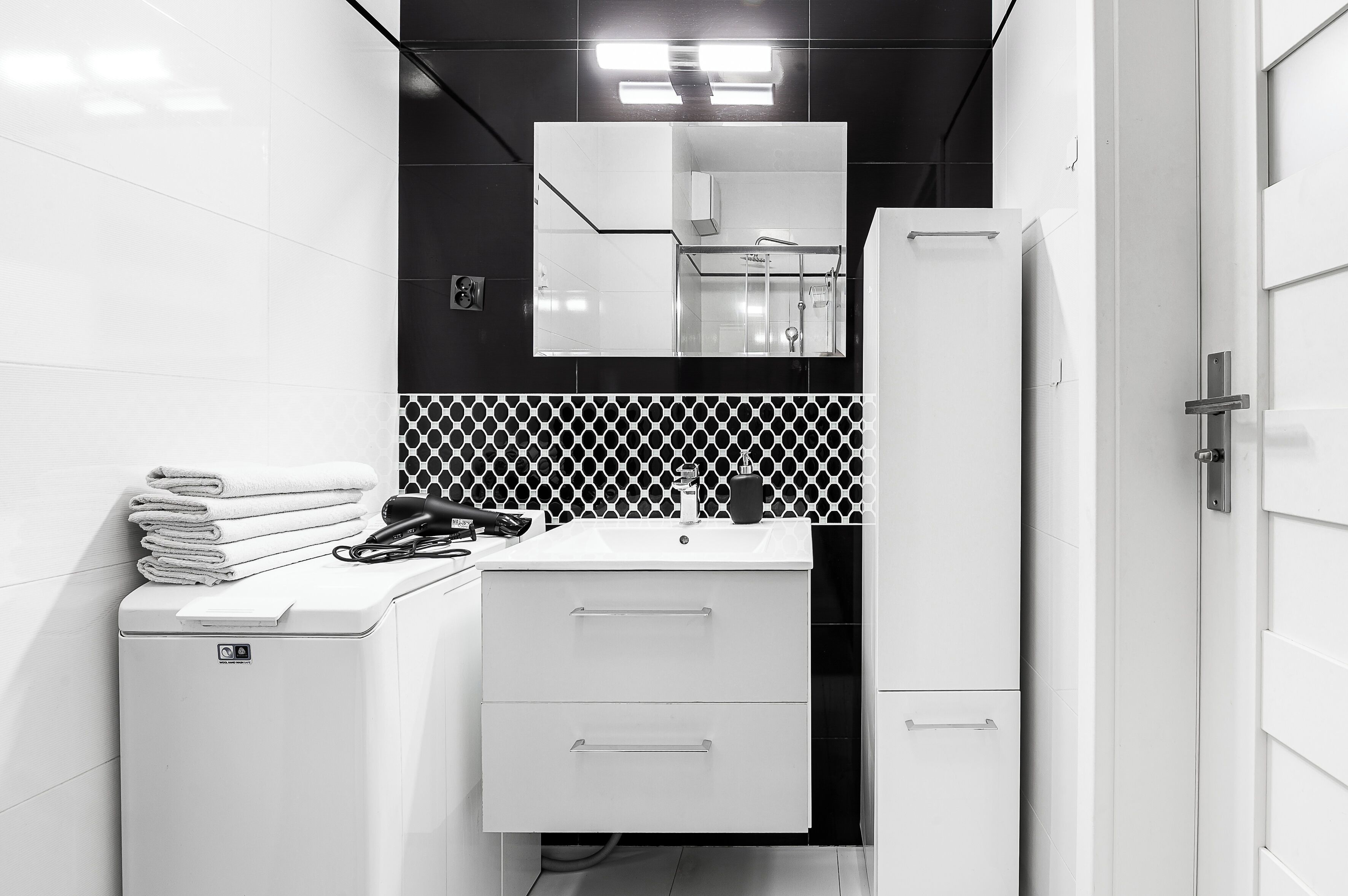 Une salle de bain moderne avec un lavabo blanc, un miroir et une pile d’serviettes.