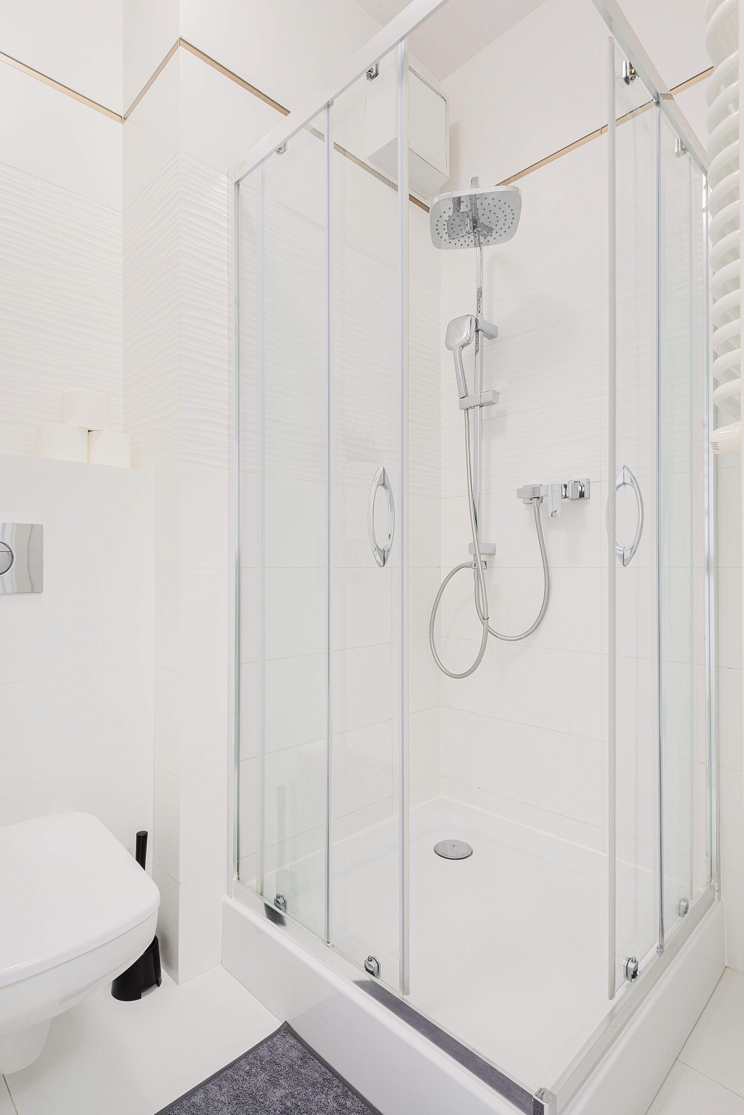 A modern bathroom with a glass-enclosed shower, a white toilet, and a tiled floor.